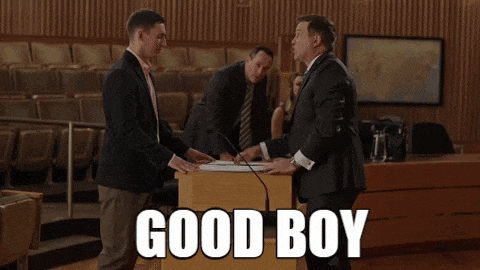 a man in a suit shakes hands with another man in front of a podium which says good boy