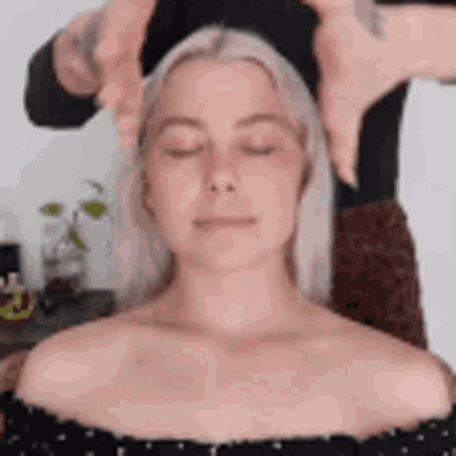 a woman is getting a head massage from a person .