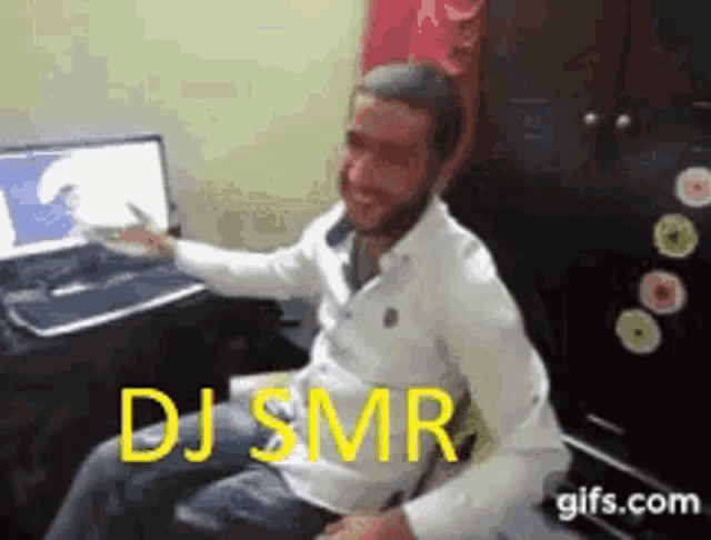 a man in a white shirt is sitting in front of a computer with the words dj smr written on the screen