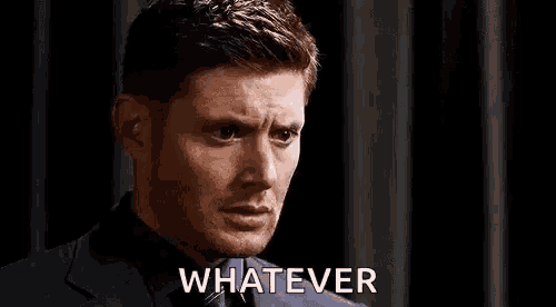 a man in a suit and tie is making a face and saying `` whatever '' .