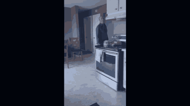 a kitchen with a stove and a microwave and a chair in the background