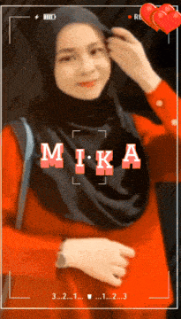 a woman wearing a hijab and a red shirt with the name mika written on it