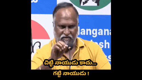 a man with a beard is speaking into a microphone in front of a sign that says ' langan ' on it