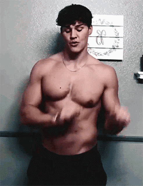 a shirtless man is standing in front of a wall with a sign that says so on it