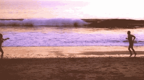 a man and a woman are running on a beach at sunset