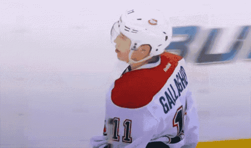 a hockey player wearing a white jersey with the number 11 on it