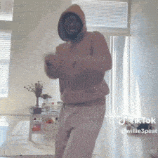 a man in a pink hoodie is dancing in a living room with the hashtag tiktok