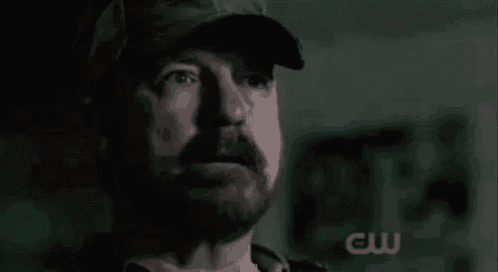 a man with a beard wearing a hat is looking at the camera .