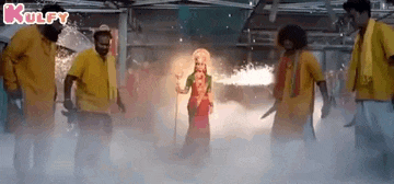a group of people in yellow shirts are standing around a woman in a costume .