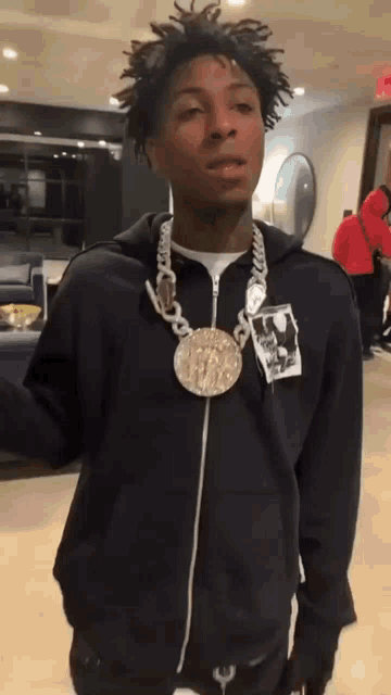 a young man wearing a black hoodie and a gold necklace