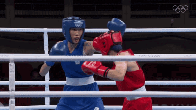 two boxers are fighting in a ring with tokyo 2020 written on the fence