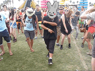 a group of people are dancing in a field with a man wearing a bunny mask on his face