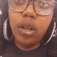 a close up of a woman 's face wearing glasses and earrings .