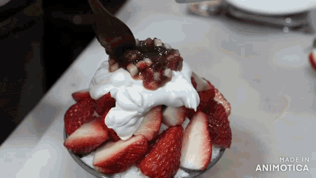 a bowl of strawberries and whipped cream is being made in animatica