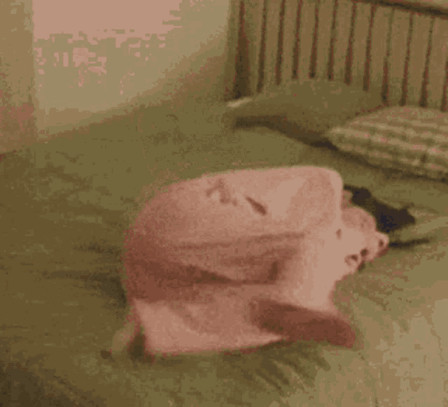 a person is laying on a bed with a pink blanket and pillows