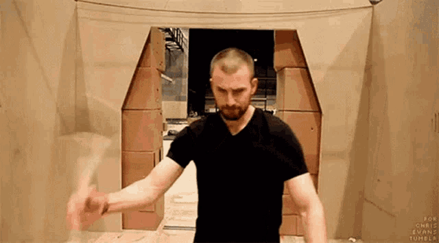 a man in a black shirt is standing in front of a cardboard doorway .
