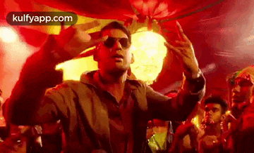 a man wearing sunglasses is dancing in front of a crowd of people in a club .