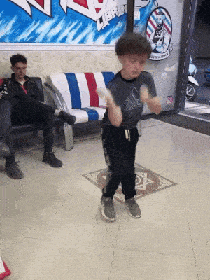 a young boy is dancing in front of a sign that says ' libre '