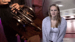 a woman sits in front of a man holding a trumpet