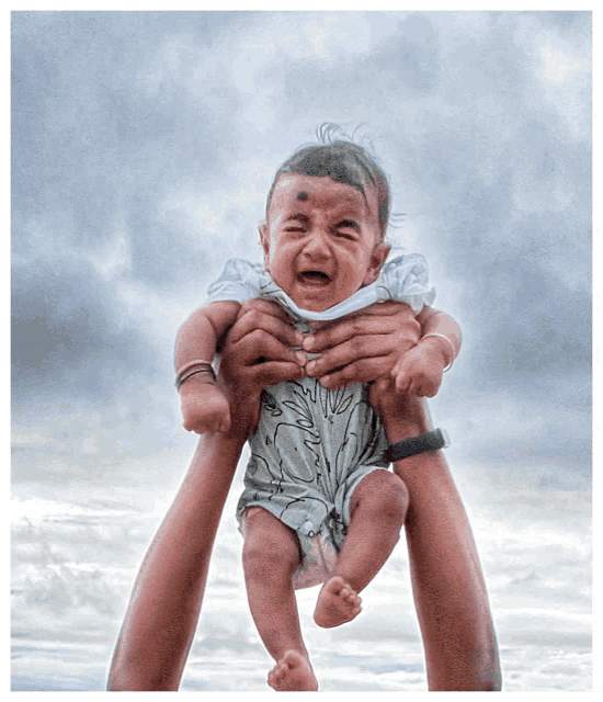 a crying baby is being held in the air by a person