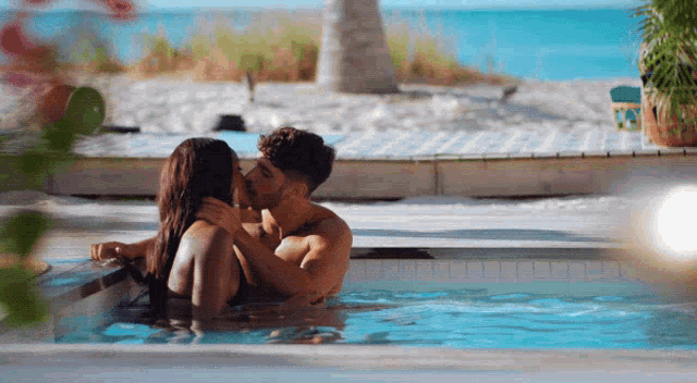 a man and woman are kissing in a swimming pool