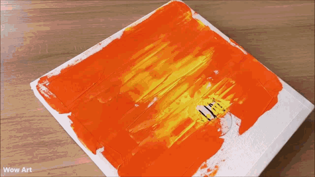 a person is applying orange paint to a canvas with wow art written on the bottom