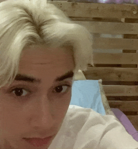 a close up of a person 's face with a wooden headboard in the background