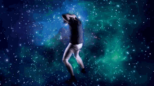 a person in a black shirt and white pants is dancing in front of a galaxy background
