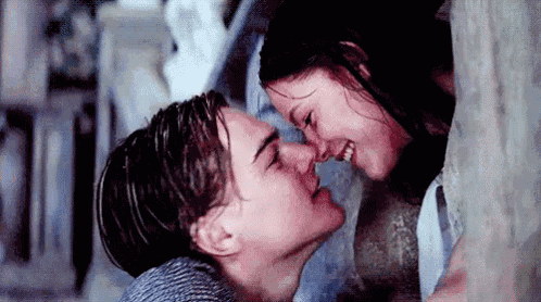 a man and a woman are kissing in front of a wall .