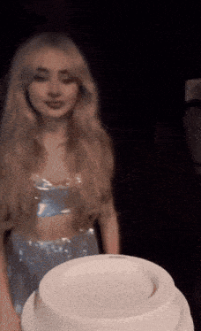 a woman in a blue dress is standing next to a white container