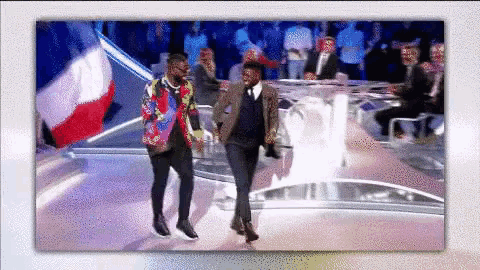 two men are dancing on a stage with a crowd watching