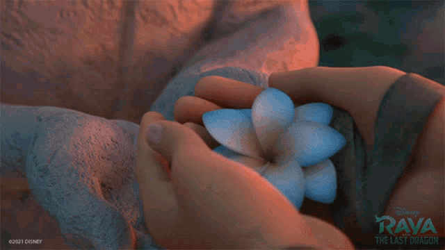 a person holding a flower with a disney logo behind them