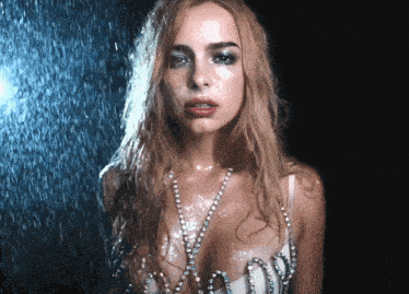 a woman with wet hair and pearls on her chest stands in the rain
