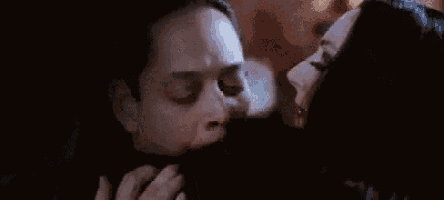 a man is laying on a woman 's lap and kissing her .