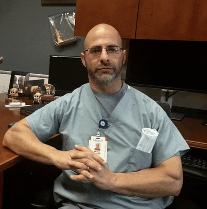 a man wearing scrubs has a name tag that says mercy on it