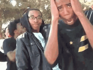two men are standing next to each other with their hands on their heads and making funny faces .