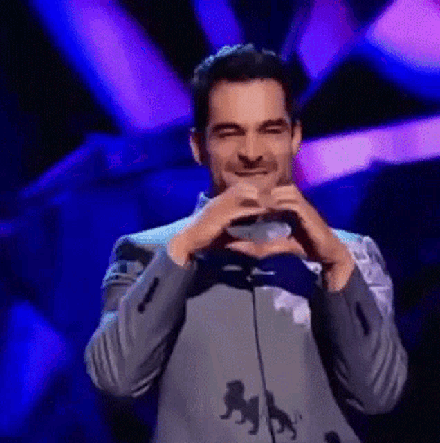 a man is making a heart shape with his hands on a stage