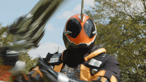 a man in an orange and black helmet is holding a green sword