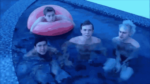 a group of young men are swimming in a pool with a pink raft .