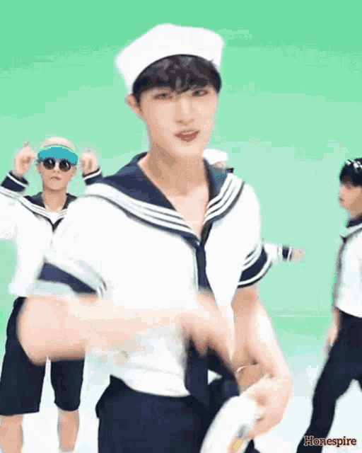a man in a sailor costume is dancing in front of a green background