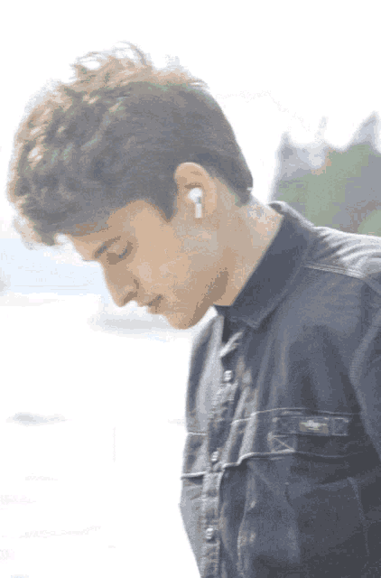 a man wearing a black shirt and white earbuds looks down