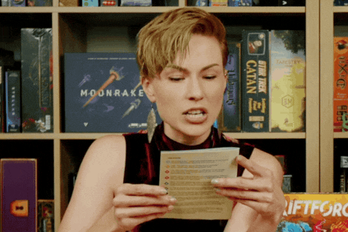 a woman is holding a piece of paper in front of a book called moonrake