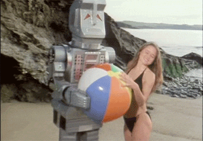 a robot holding a beach ball next to a woman