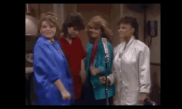 a group of women are singing into microphones while standing next to each other .