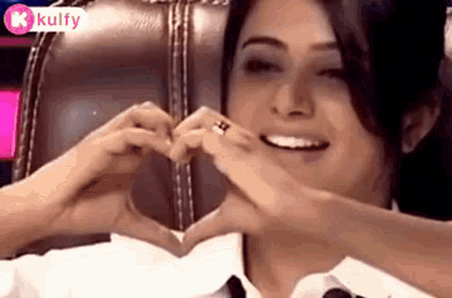 a woman is making a heart with her hands and smiling .
