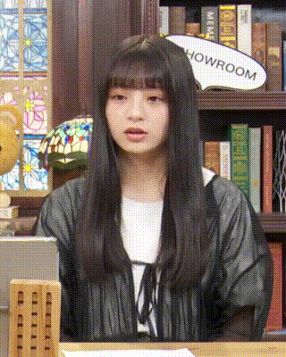 a woman sitting in front of a bookshelf with a sign that says showroom on it