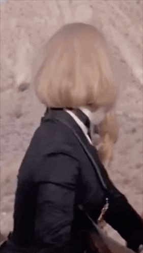 a woman in a suit and tie is riding a horse in the desert .