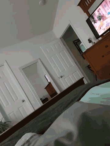 a bedroom with a tv on the wall and a dresser