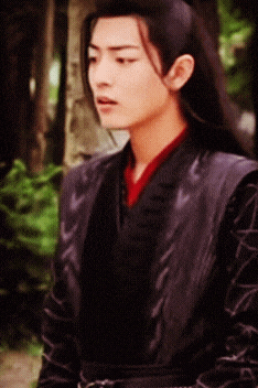 a man with long black hair is wearing a black vest