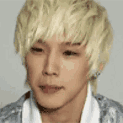 a young man with blonde hair and a white shirt is making a face .